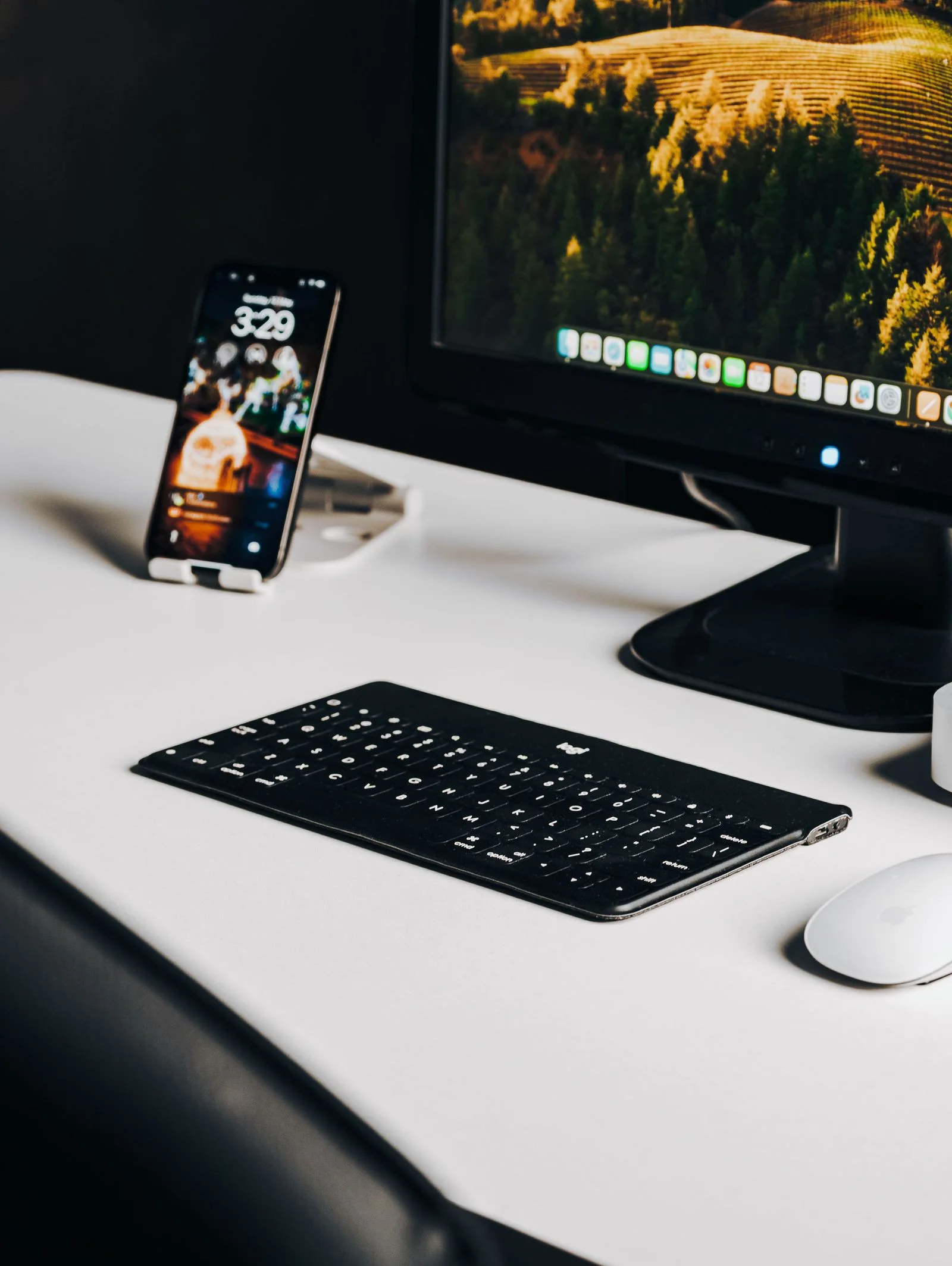 Keyboard and smartphone beside a desktop display